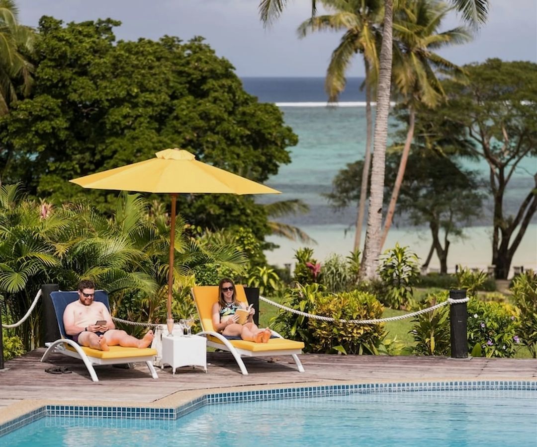 People reading by pool next to the beach