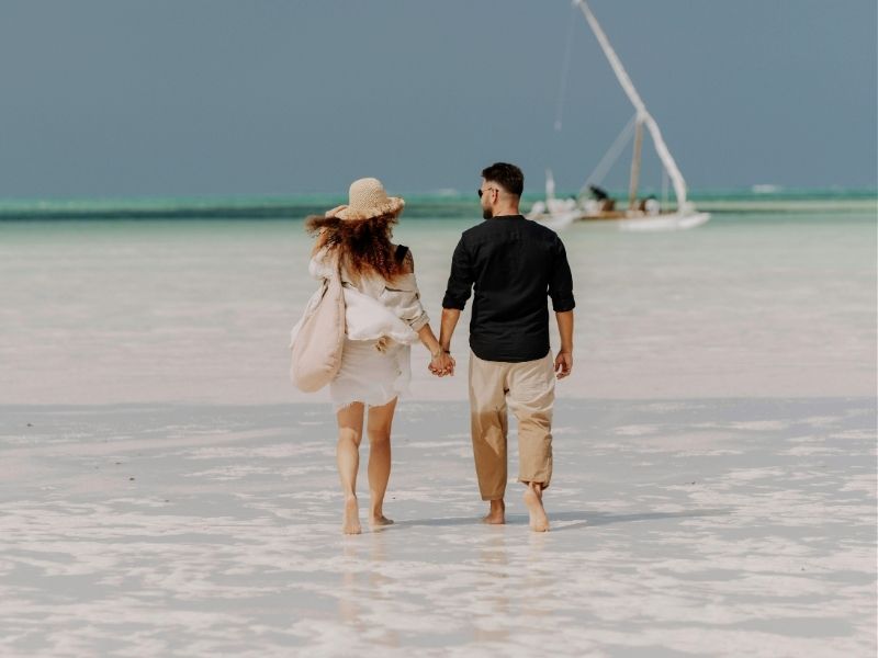 couple walking on whote sand beach