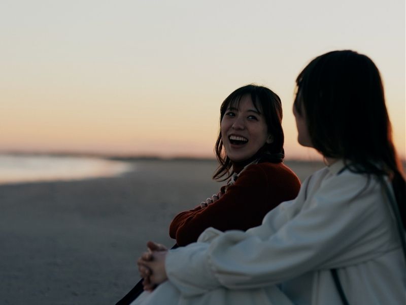 smiling friends watching sunset on beacg