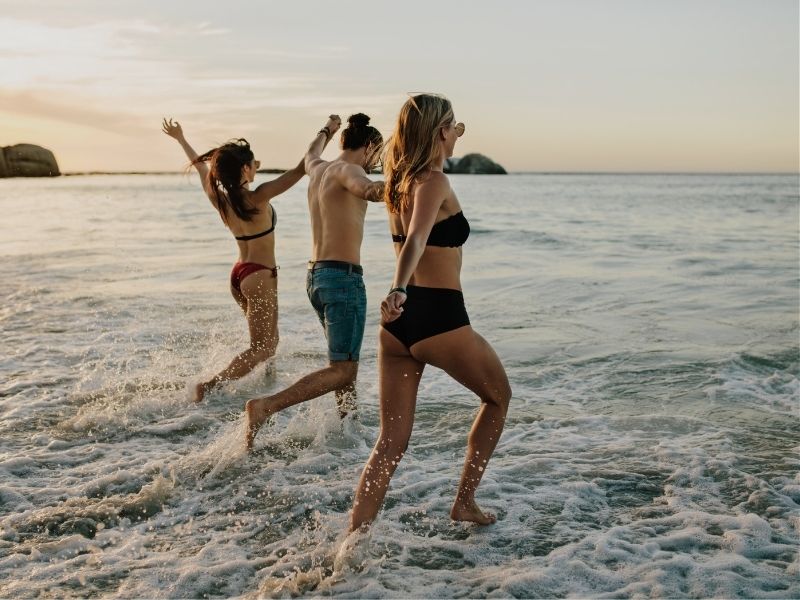 young peopl running into the ocean for a swim
