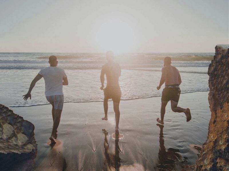 men running on beach into the ocean