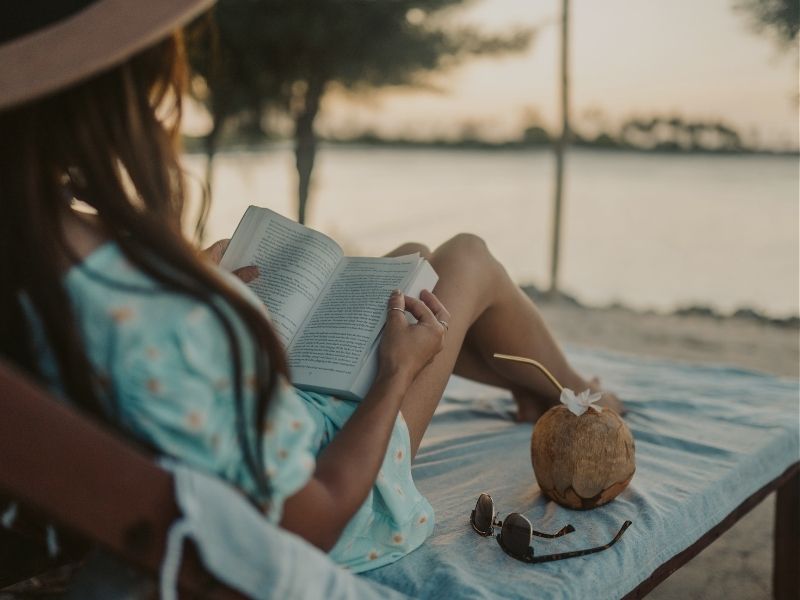 lady relaxing by the beaaching reading