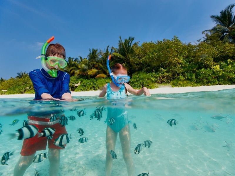 siblings snorkling with fish