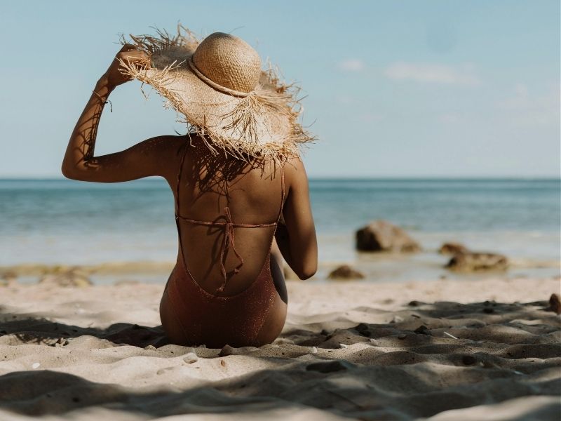 women in straw hat sitting on beach