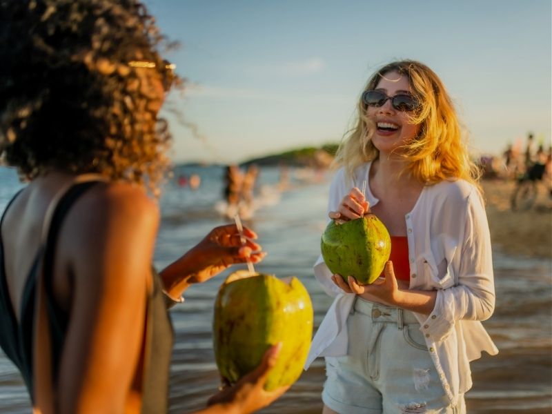 friends on beach drinking coconuts