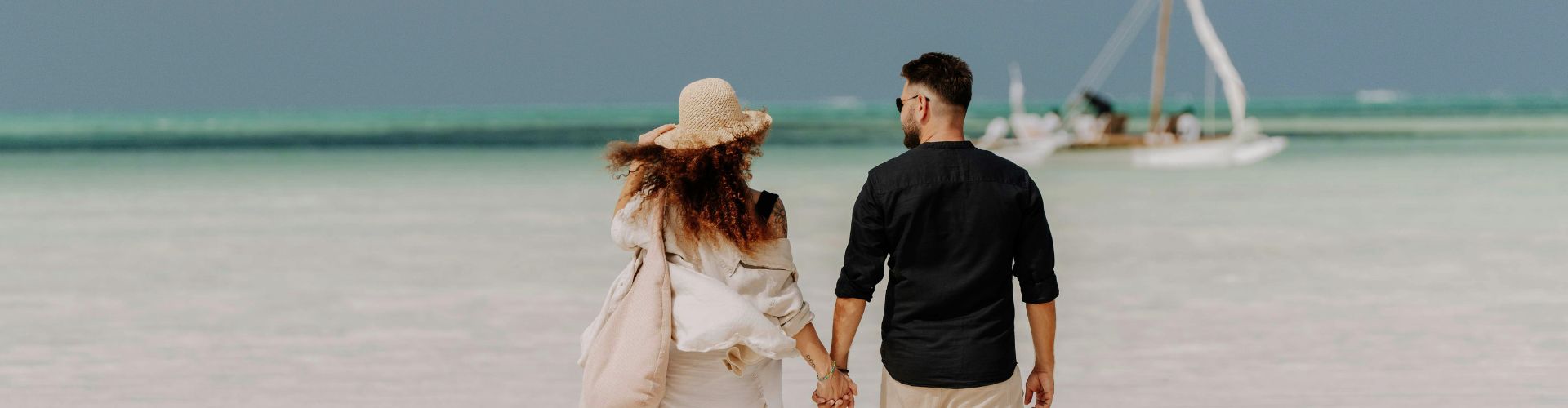 couple walking on white sand beach