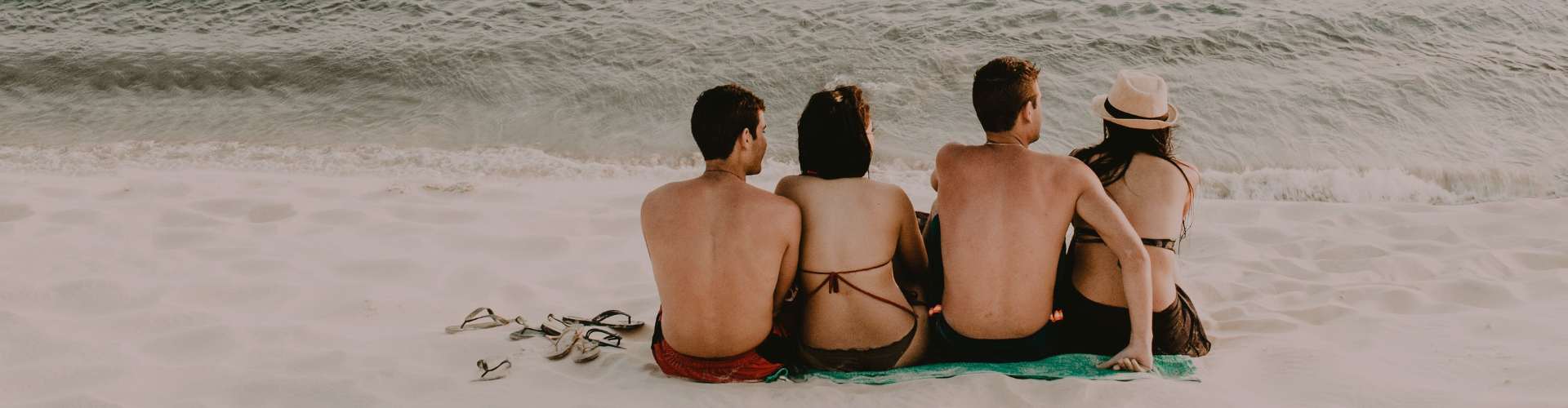 friends sitting on beach watching waves