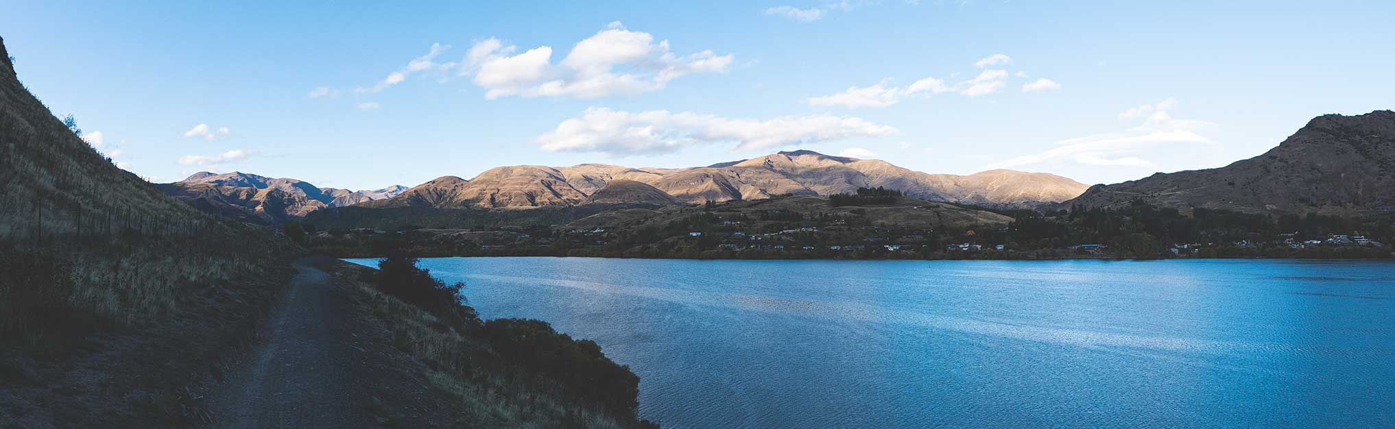 Lake hayes new zealand beautiful water calm nature surrounded by mountains blue clear day sunshine